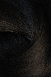 A close-up texture shot of dark, glossy hair with subtle warm brown undertones and a soft, swirled arrangement. (Jet Black / #1)