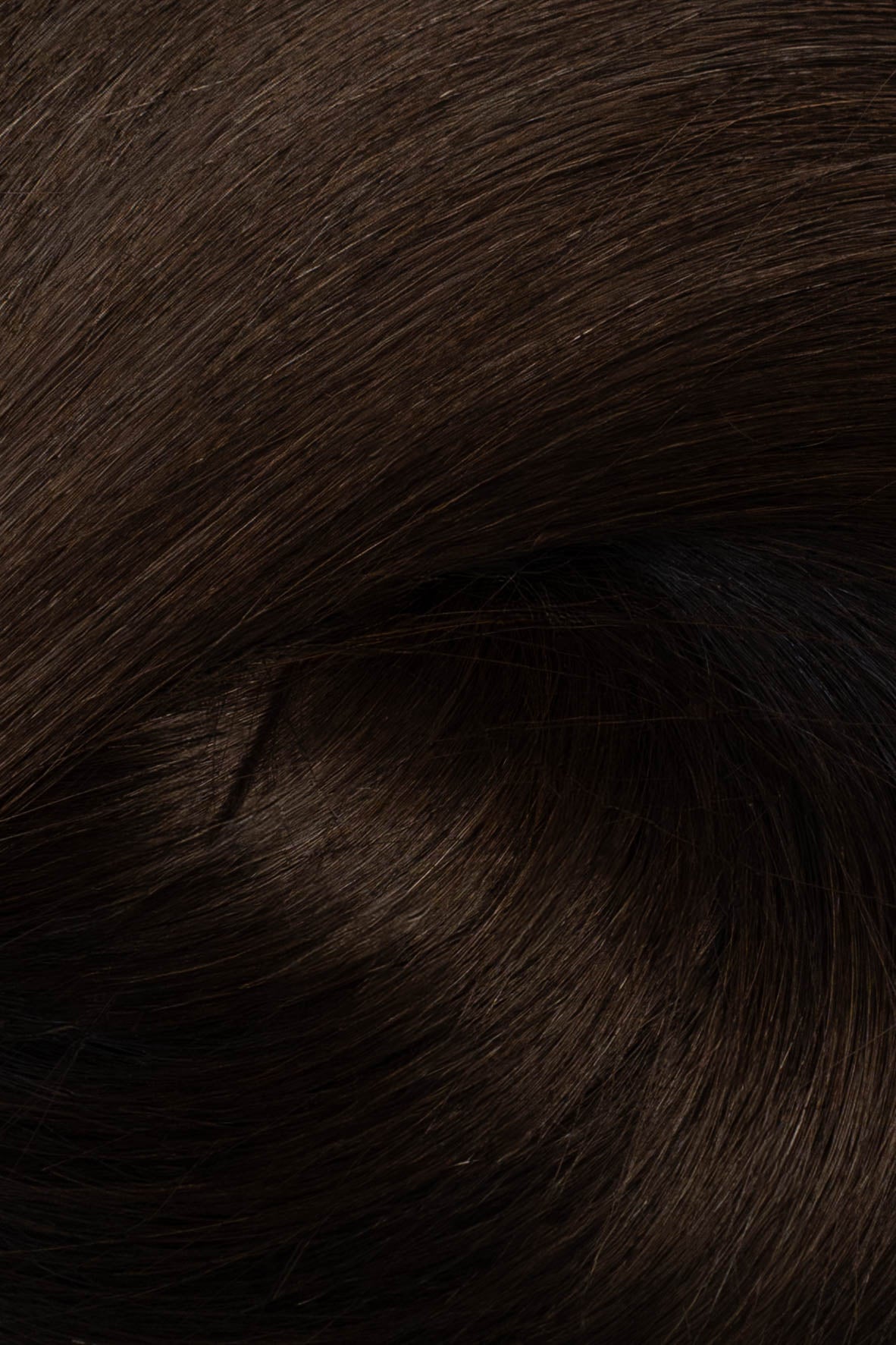 A close-up texture shot of dark brown hair, showing the fine strands and subtle sheen. (Soft Black / #1b)