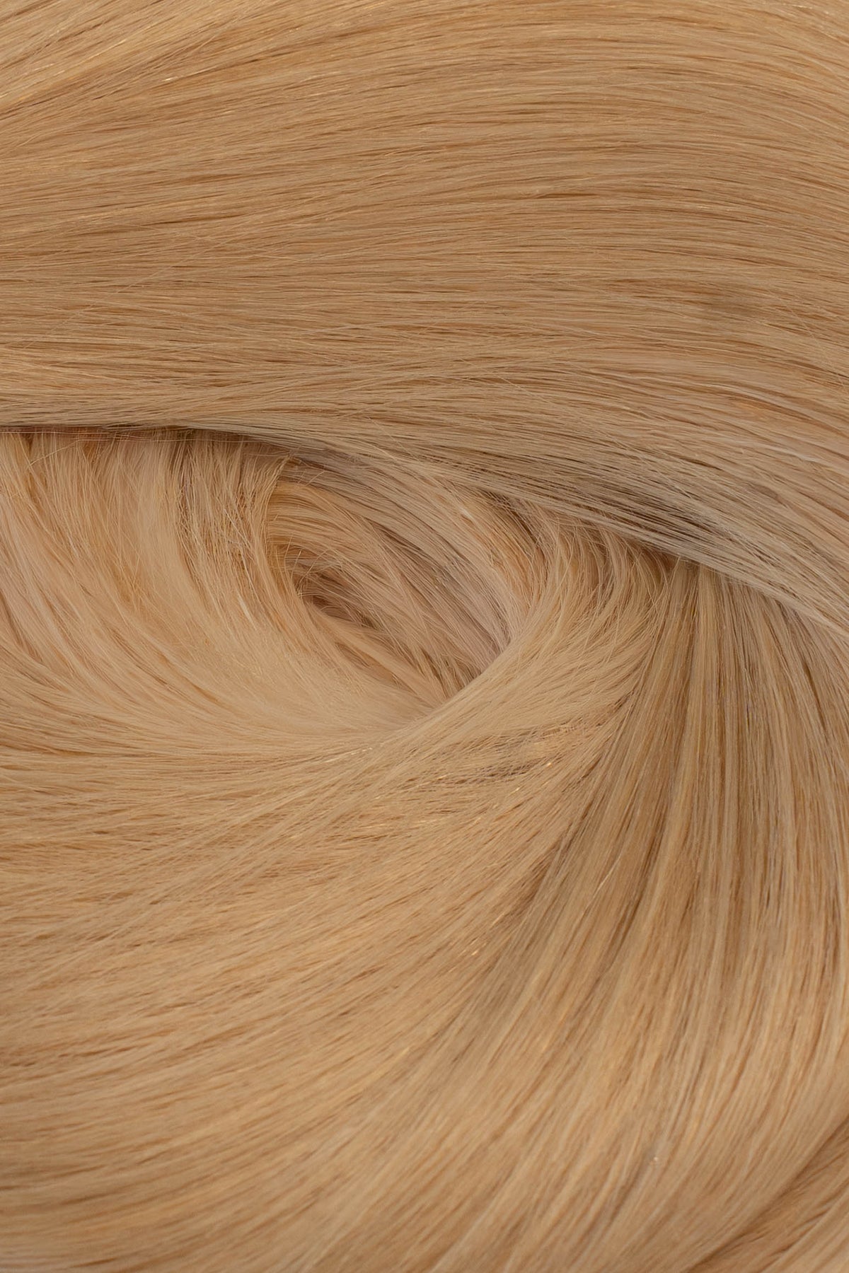 A close-up texture shot of light blonde hair, showing the fine strands and subtle warm golden-blonde tones arranged in a soft swirl. (California Blonde / #24)