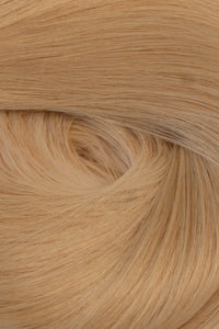 A close-up texture shot of light blonde hair, showing the fine strands and subtle warm golden-blonde tones arranged in a soft swirl. (California Blonde / #24)