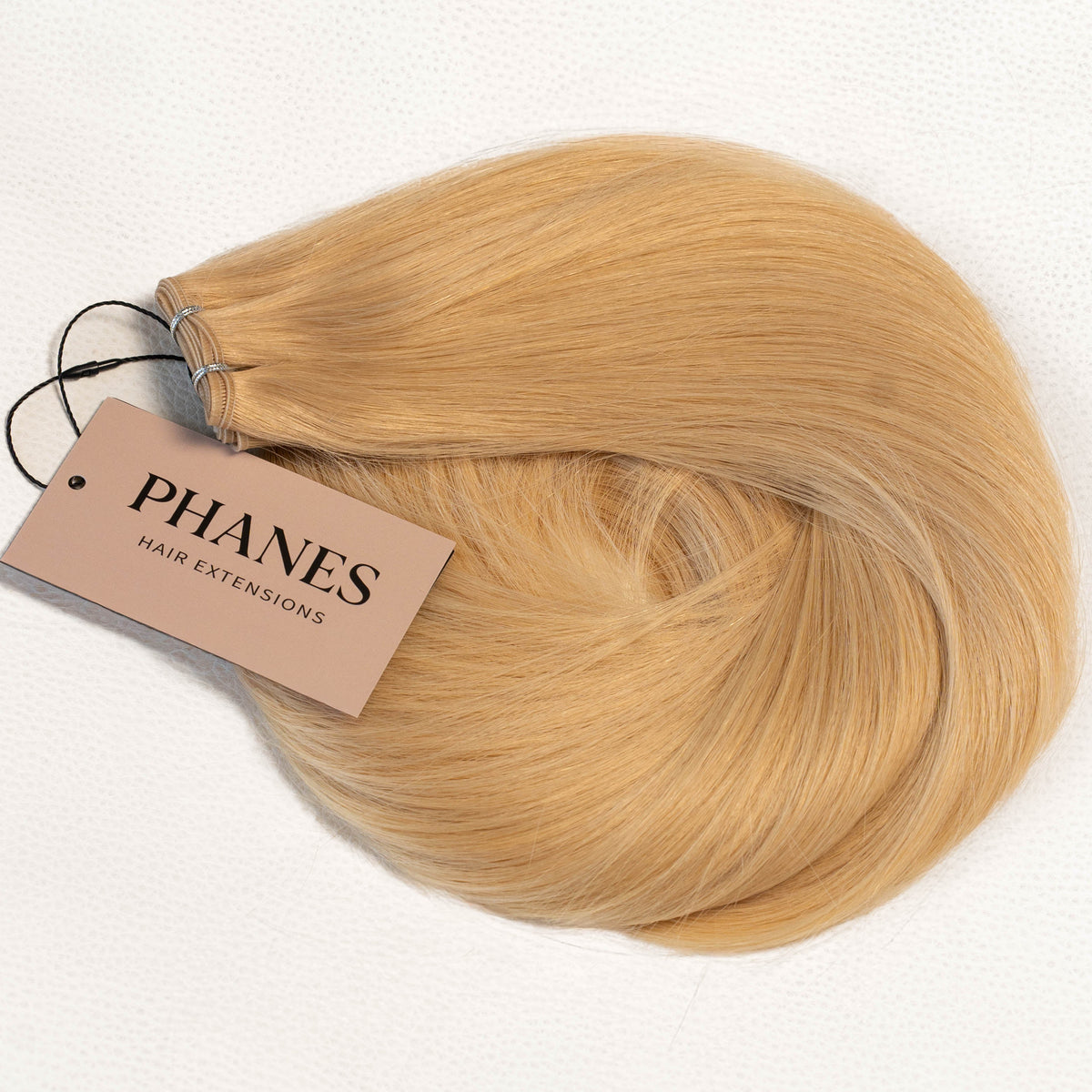 A bundle of straight blonde hair extensions with a beige paper tag reading PHANES HAIR EXTENSIONS, photographed on a clean white background. (California Blonde / #24)