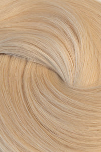 A close-up of light blonde hair strands arranged in a soft spiral pattern, showing the texture and color of the hair.  (Ice Blondest / #24A)