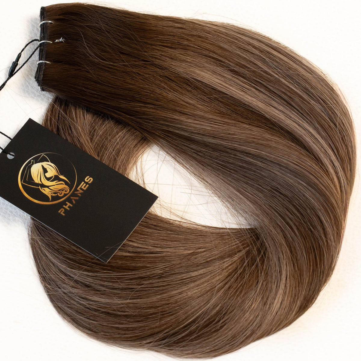 A bundle of brown hair extensions with a black brand tag attached, displayed on a clean white background. (Mushroom Brown / B2/9.1)