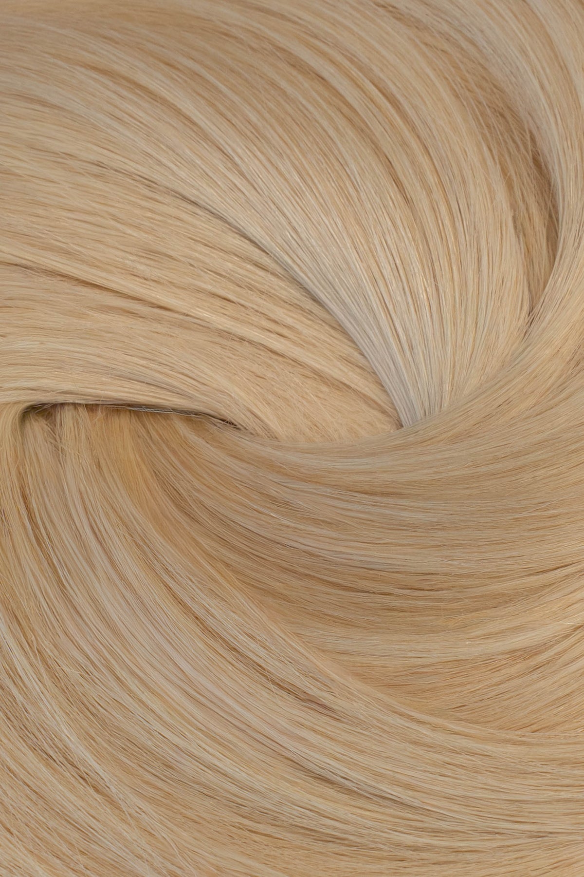 A close-up texture shot of light blonde hair, showing the fine strands and subtle golden-beige tones arranged in a soft swirl. (Blondest Blonde / #60)