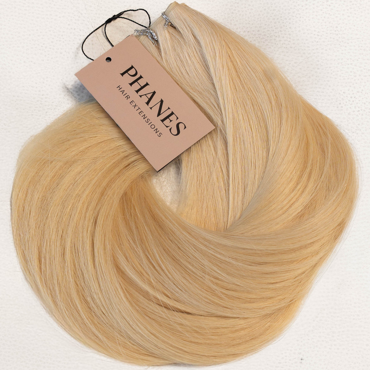A bundle of blonde hair extensions with a beige paper tag reading PHANES, displayed on a clean white background. (Blondest Blonde / #60)