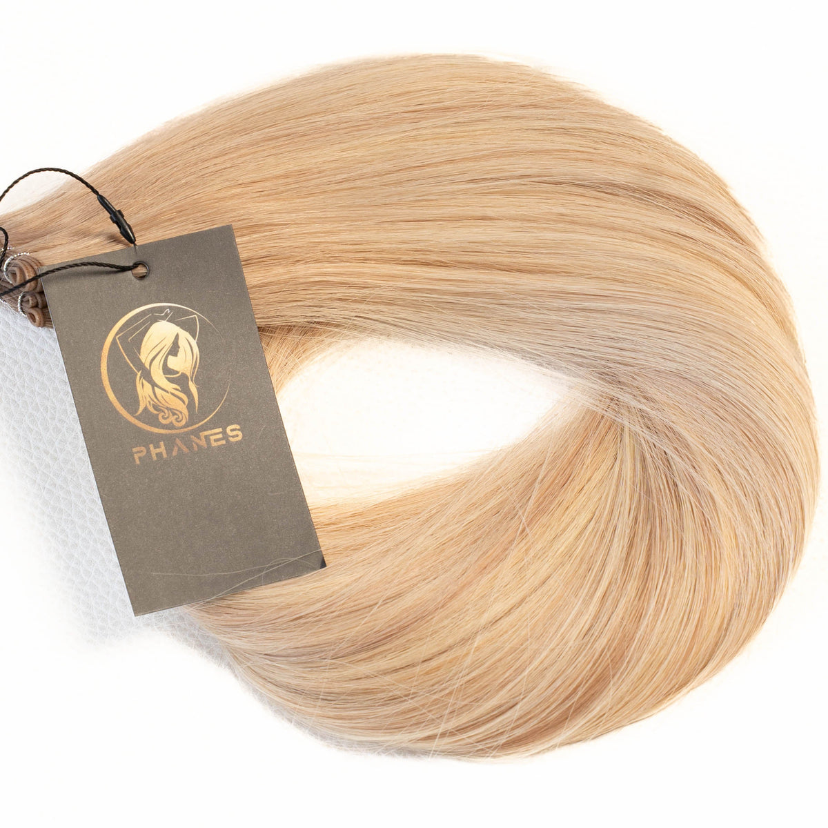 A bundle of light blonde hair extensions with a dark brown paper tag attached, displayed on a clean white background. (Beige Blonde Lowlights / #B9.1/60A)