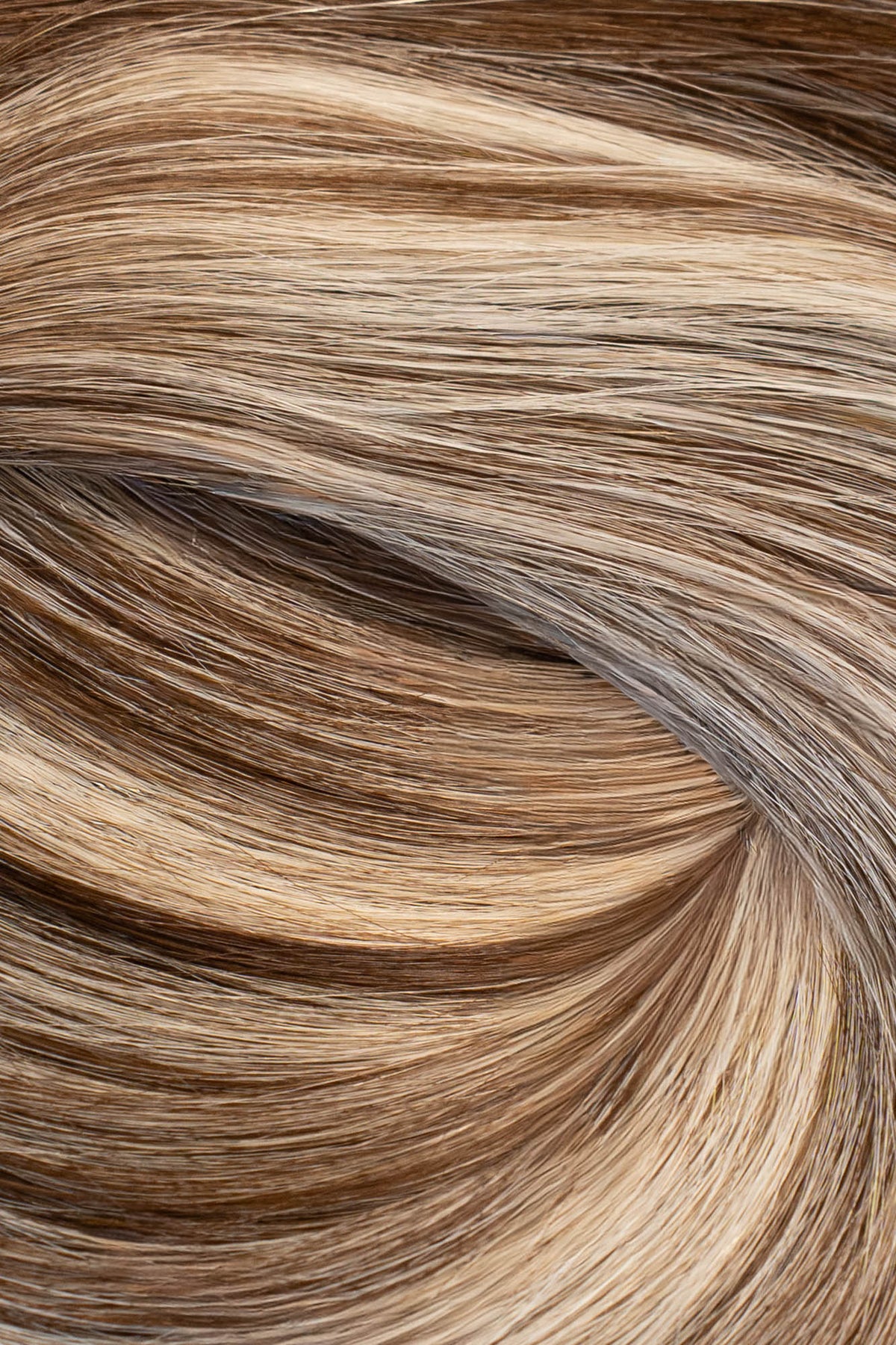A close-up texture shot of wavy hair with a blend of light brown, golden blonde, and dark brown tones. (Boston Balayage B2/60)