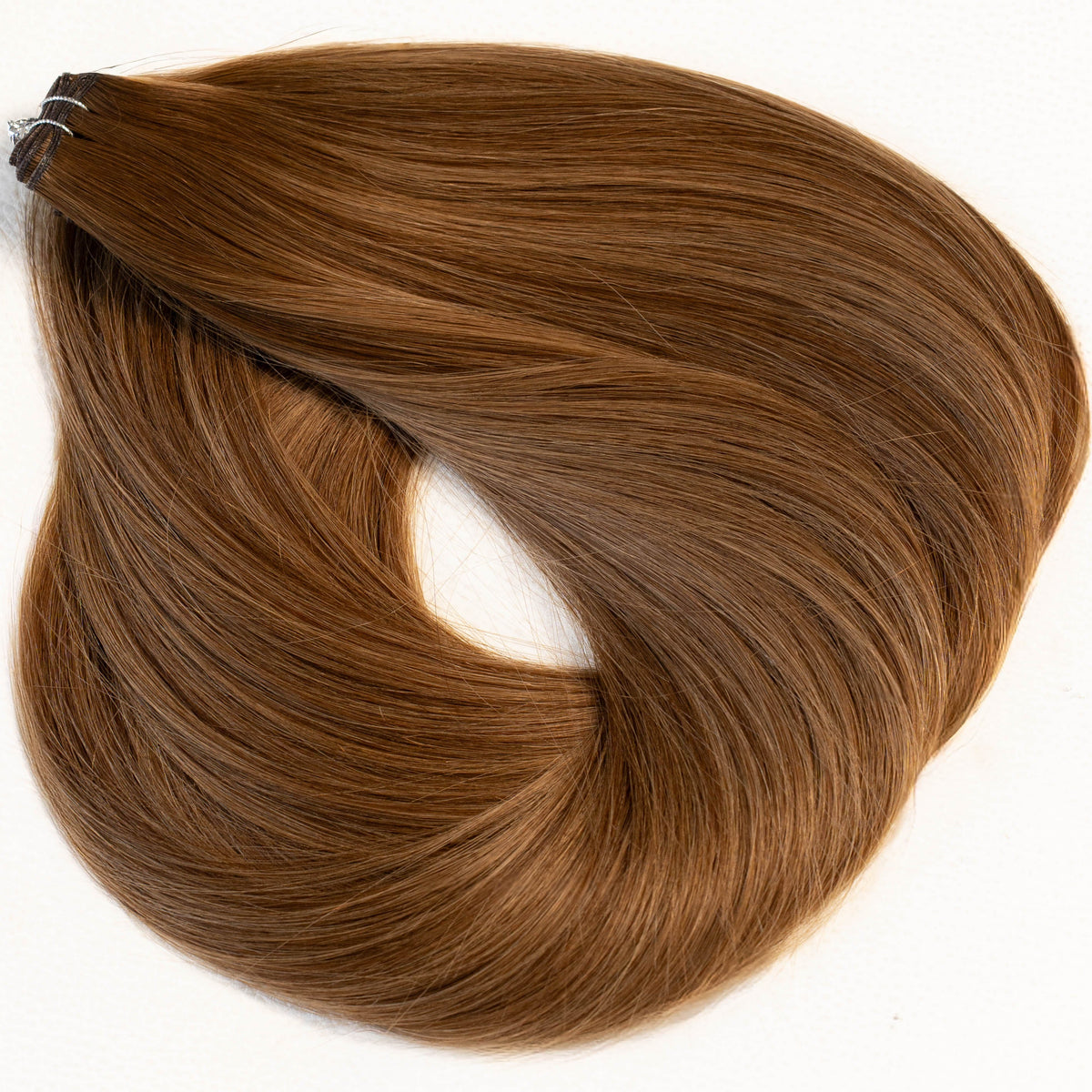 A single bundle of medium brown hair extension clips on a plain white background. (Rooted Caramel / #B4/80