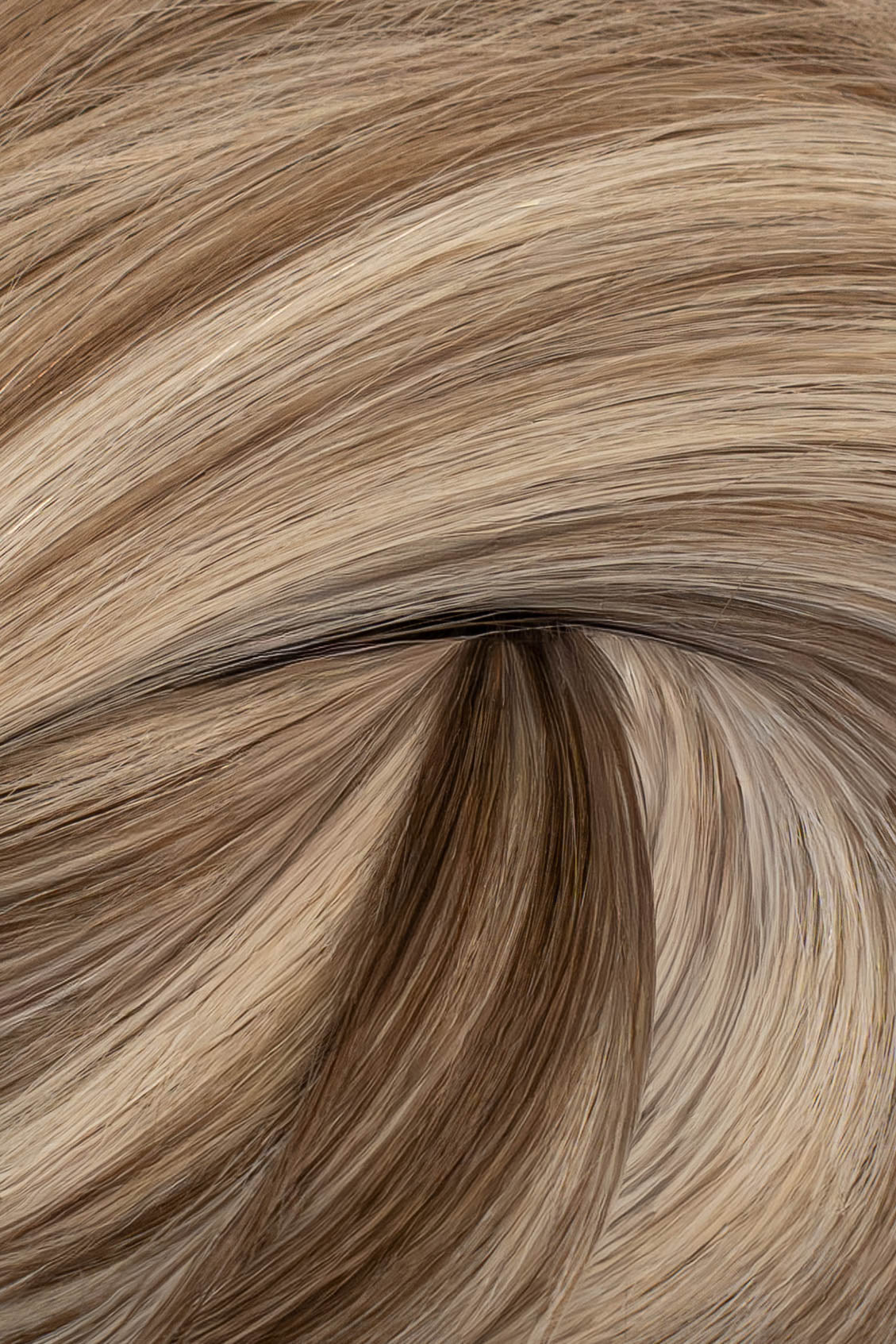 A close-up texture shot of wavy hair in a light ash blonde color with subtle brown and beige highlights. (Ash Piano / FV)