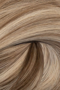A close-up texture shot of wavy hair in a light ash blonde color with subtle brown and beige highlights. (Ash Piano / FV)