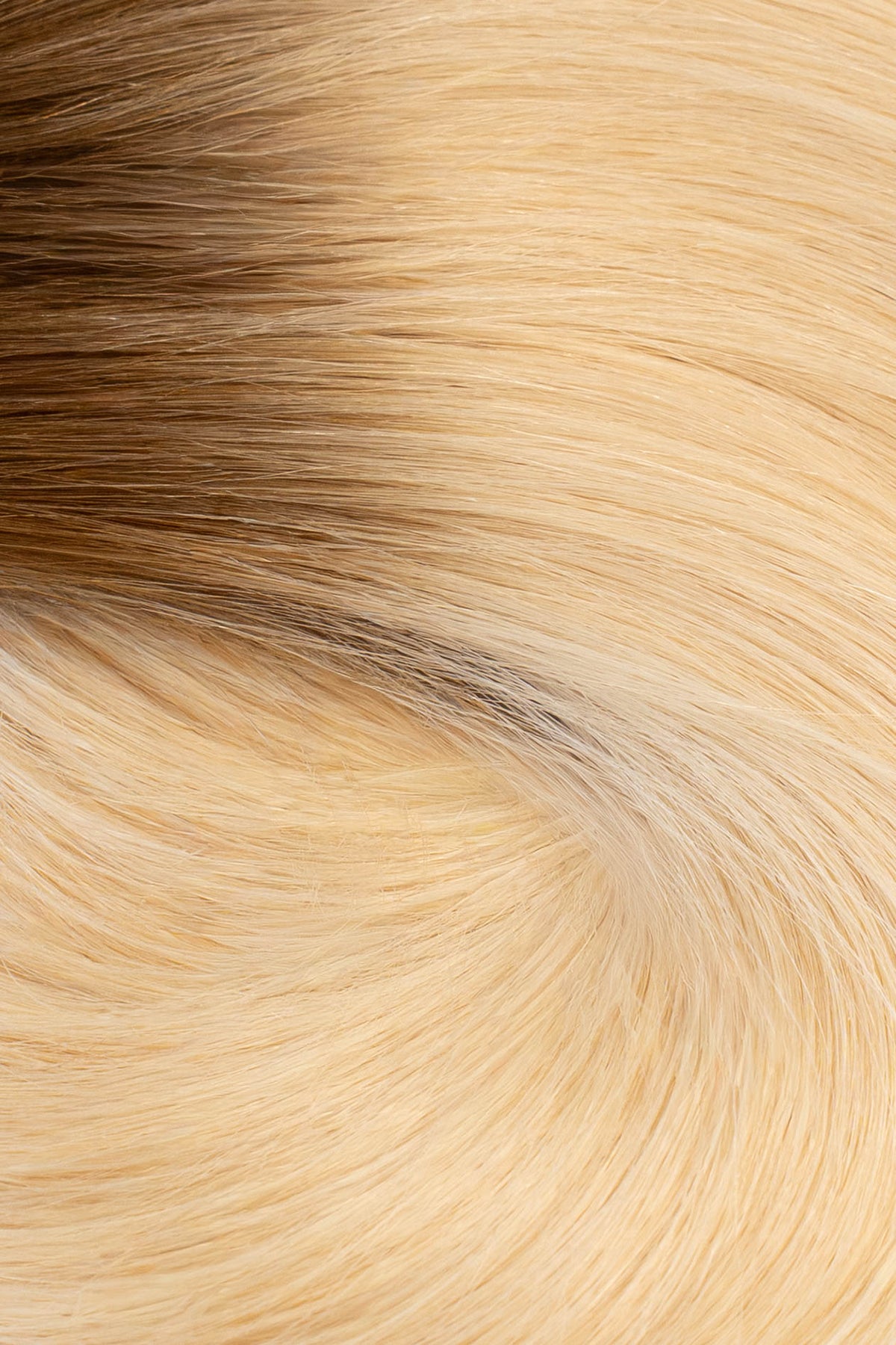 A close-up texture shot of straight hair with a warm blonde to light brown ombré color transition. (Rooted Blonde / #T4/60)