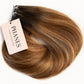 A hair extension bundle with a tan tag reading PHANES, showing a warm brown to blonde ombré color, photographed on a solid white background. (Carmel Mocha / TBF)