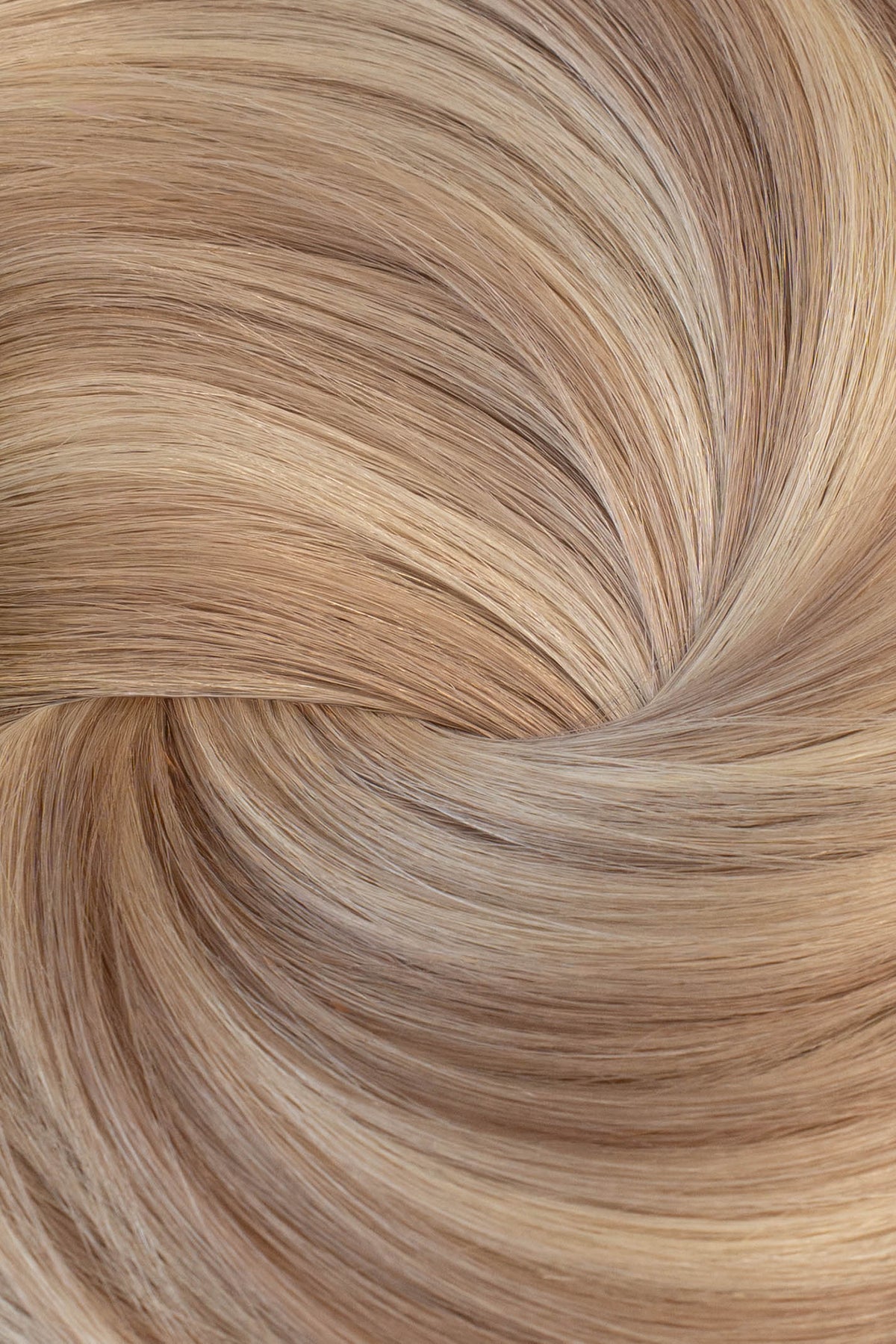 A close-up texture shot of light blonde hair styled in a spiral pattern, showing the fine strands and warm golden-blonde color. (Icy Balayage / #TSK)